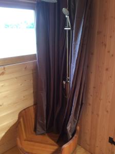 - une douche dans une chambre avec un rideau et un microphone dans l'établissement Shanti Lac Cabanes gîtes insolites et espace bien-être Bordeaux, à Berson