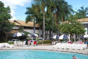 una piscina con sillas blancas, mesas y sombrillas en diRoma Resort - Achei Ferias, en Caldas Novas