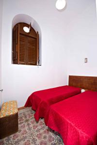 a bedroom with two beds with red sheets and a window at BILOCALE VERDI A C/MARE GOLFO in Castellammare del Golfo