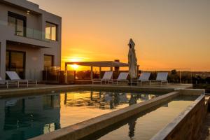 a villa with a swimming pool at sunset at Thea Sunrise Luxury Villa with Heated Eco Pool in Kallithea Rhodes