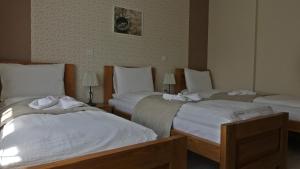 2 camas en una habitación de hotel con sábanas blancas en Alice Panzió Gold, en Kalocsa