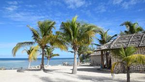 a beach with palm trees and a building at Laguna Blu - Resort Madagascar in Andavadoaka