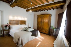 a bedroom with a white bed and a wooden cabinet at Dimora Dell'Erbe Apartments in Montepulciano
