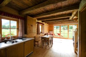 eine Küche mit einem Waschbecken und einem Tisch mit Stühlen in der Unterkunft Alpi Giulie Chalets in Valbruna