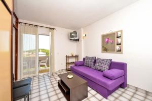 ein Wohnzimmer mit einem lila Sofa und einem Tisch in der Unterkunft Ana Apartments in Kukljica