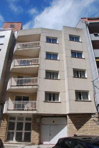 un immeuble d'appartements avec un garage en face de celui-ci dans l'établissement Apartamentos Granxola, à Sanxenxo