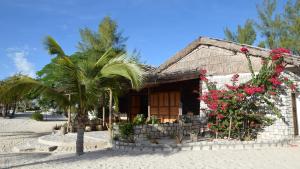 a building with flowers and a palm tree in front of it at Laguna Blu - Resort Madagascar in Andavadoaka