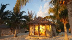 un pequeño edificio en la playa con palmeras en Laguna Blu - Resort Madagascar en Andavadoaka