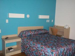 - une chambre avec un lit et un mur bleu dans l'établissement Skyline Inn, à Conway
