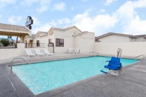 a swimming pool with a blue chair in front of a house at Days Inn by Wyndham Kingman West in Kingman