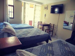 1 dormitorio con 2 camas, mesa y TV en El Balcon Hostal, en Ayacucho