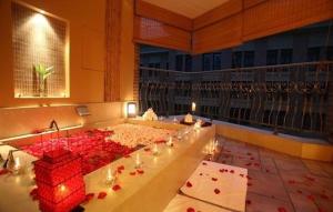 a large bath tub filled with red flowers on a balcony at Greenland Yuhao Hot Spring Hotel in Jiangning