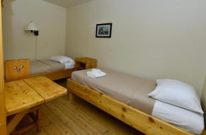 a room with two beds and a wooden table at The Bunkhouse in Dawson City