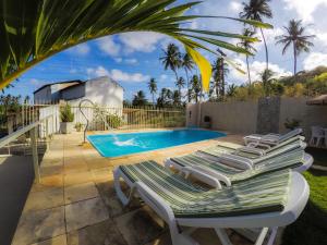 a group of lounge chairs next to a swimming pool at Flat Vila dos Milagres in São Miguel dos Milagres
