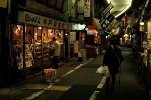 een vrouw die door een straat loopt in een steegje bij Hostel TangaTable in Kitakyushu