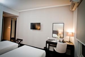 a hotel room with a desk and a bed and a mirror at Samala Hotel Jakarta Cengkareng in Jakarta