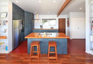 a kitchen with a blue island with two bar stools at Vista Twenty One in Onetangi