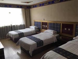 a hotel room with three beds and a window at Overseas Tibetan Hotel in Xiahe