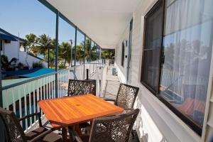 Una mesa y sillas de madera en un balcón. en Apollo Jewel Beachfront Apartments, en South Mission Beach