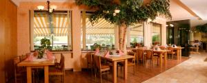 un ristorante con tavoli e sedie in legno e finestre di Hotel Reitzentrum Hausruckhof ad Ampflwang im Hausruckwald