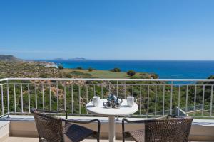 Triopetra View Villas في تريوبيترا: طاولة وكراسي على شرفة مع المحيط