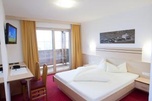 a hotel room with a bed and a desk and a window at Haus Mühlbach in Fiss