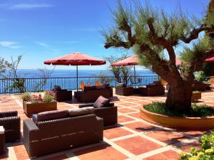 a patio with couches and an umbrella and a tree at Rigat Park & Spa Hotel - Adults Recommended in Lloret de Mar