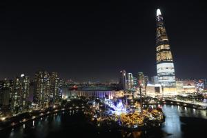 a large clock tower towering over a city at night at Lotte World Lake View Loft in Seoul