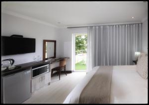 a bedroom with a bed and a desk and a television at Impa-Lala Country Estate in Bloemfontein