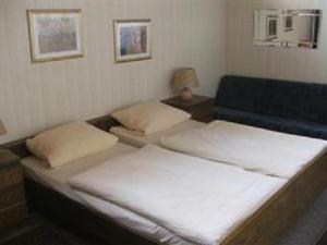 Habitación con 2 camas y sofá azul en Hotel Heidehaus en Mönchengladbach