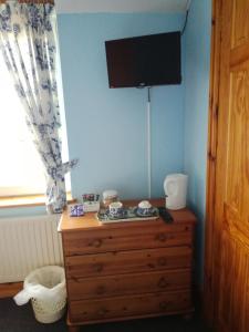 LlangadogにあるTy Newyddの木製ドレッサー付きのベッドルーム(壁にテレビ付)