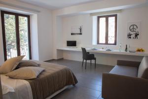 a white bedroom with a bed and a desk at La Chambre in Paola