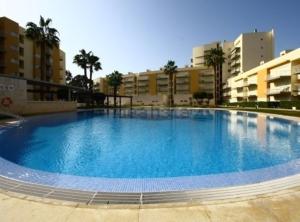 a large blue swimming pool in front of some buildings at Apartamento Vilamoura in Quarteira