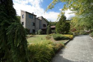 a house with a brick walkway in front of a yard at Villa le Noci in Bettola
