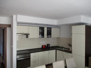 a kitchen with white cabinets and black counter tops at Penzion Milada in Všetaty