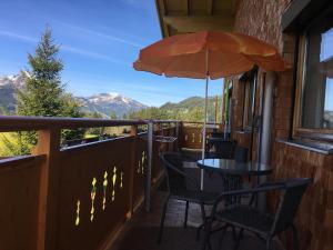 einen Balkon mit einem Tisch, Stühlen und einem Sonnenschirm in der Unterkunft Haus Lorenz in Grän