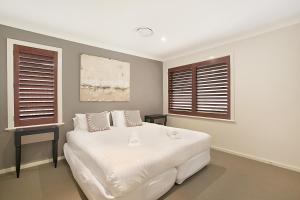 a bedroom with a large white bed and two windows at Peppertree Lodge Hunter Valley in Rothbury