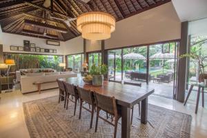 a dining room with a wooden table and chairs at Chimera Villas in Seminyak