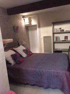 a bedroom with a bed with a purple blanket and pillows at La Maison du Bien Etre in Aigues-Mortes