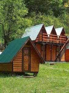 a large wooden cabin with a green roof at Rafting Campsite Stari Dud in Foča