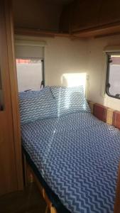 Bett in einem Zimmer mit blauer Decke in der Unterkunft Caravan Apartment in Tinajo