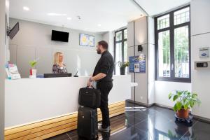 un homme debout au comptoir avec ses bagages dans l'établissement Odalys City Nice Le Palais Rossini, à Nice