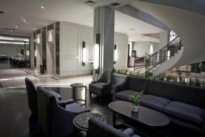 a lobby with couches and tables and a staircase at Samala Hotel Jakarta Cengkareng in Jakarta