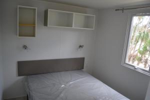 a bed in a room with a white wall at Camping Valencia el Saler in El Saler