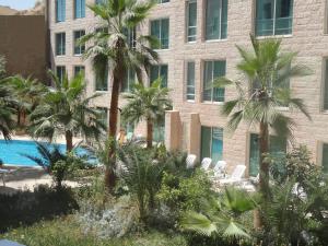 a building with palm trees in front of a pool at Petra Palace Hotel in Wadi Musa