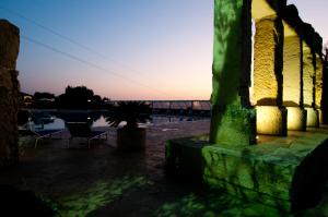 ein Gebäude mit einer grünen Säule vor einem Wasserkörper in der Unterkunft Agriturismo La Maddalena in Acate