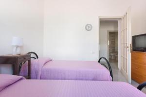a bedroom with two beds with purple sheets and a television at Riva degli Angeli by BarbarHouse in Punta Prosciutto