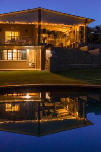 a house with lights reflecting in the water at night at La Vida Luka - Luxury Guesthouse in Pretoria