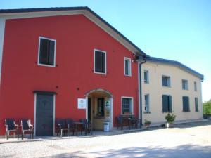un edificio rojo con sillas y mesas delante de él en Agriturismo Le Gazze, en Camposanto