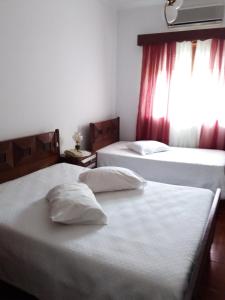 two beds in a hotel room with a window at Pensão São Jorge in Caldas de São Jorge
